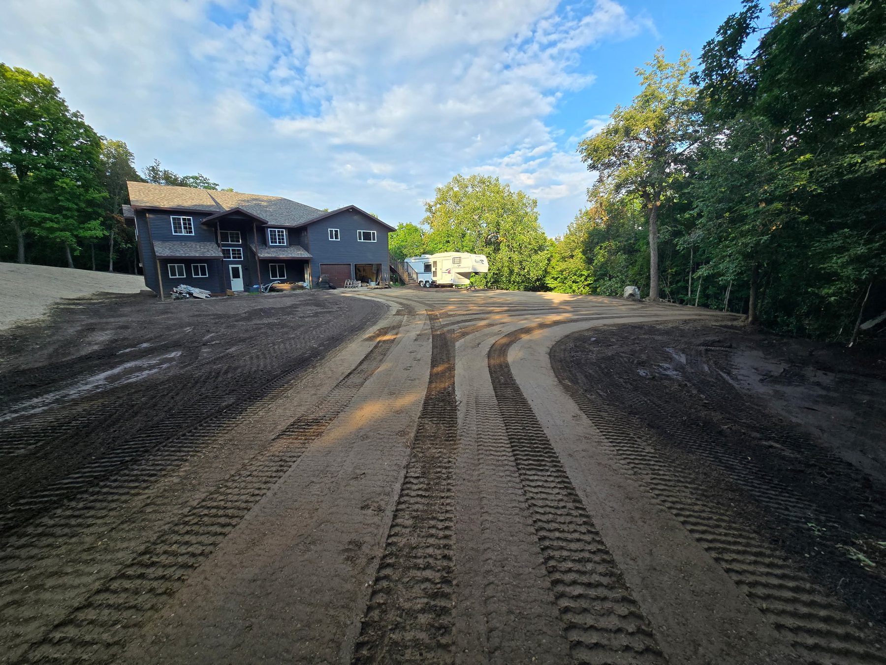 Newly graded gravel driveway leading toward a residence