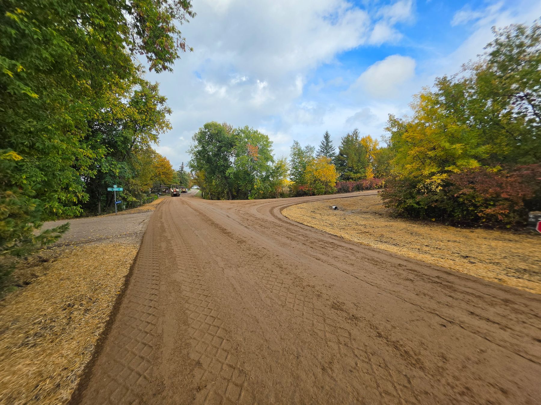 Freshly rebuilt gravel road curving through fall trees