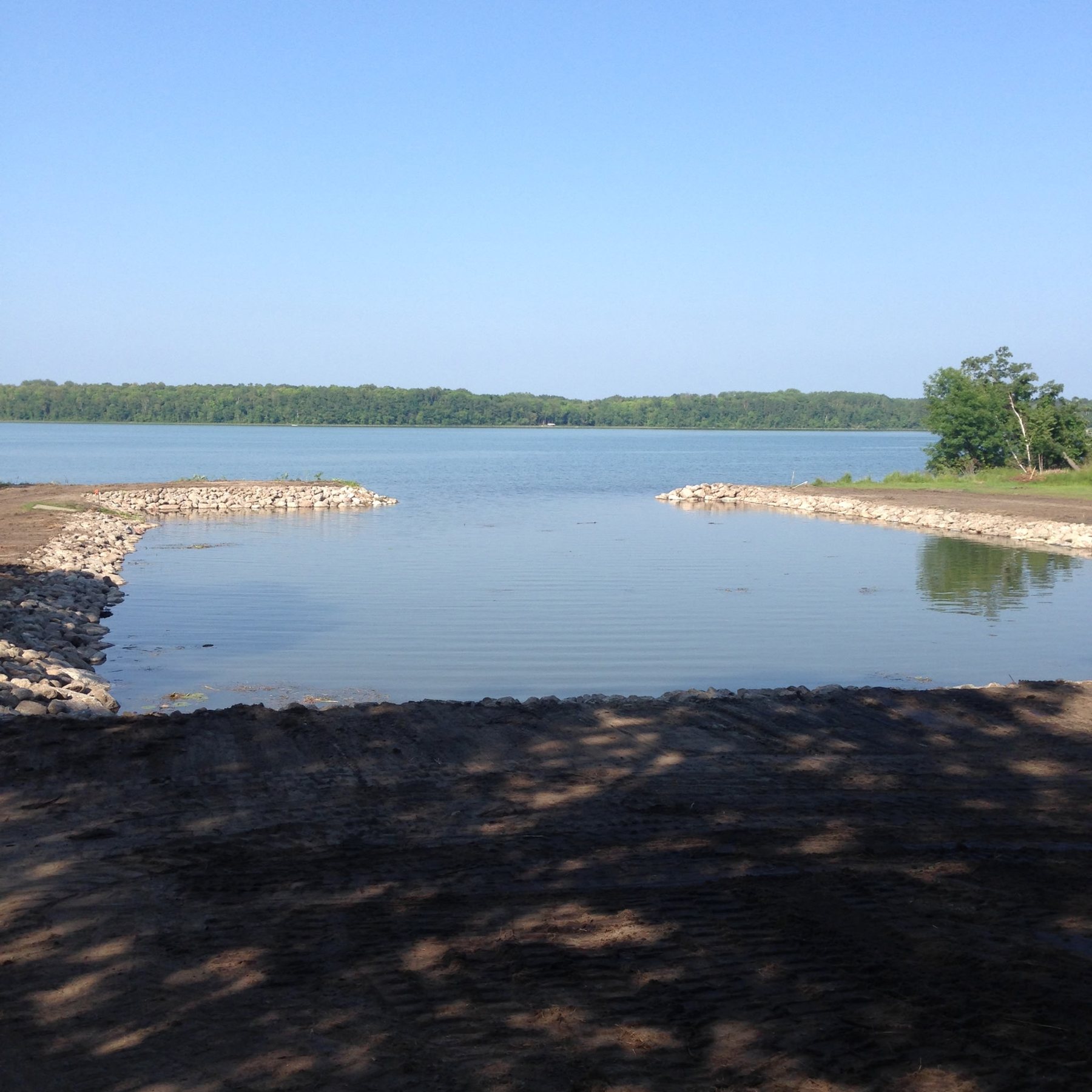 Rock-lined shoreline beside a calm lake cove