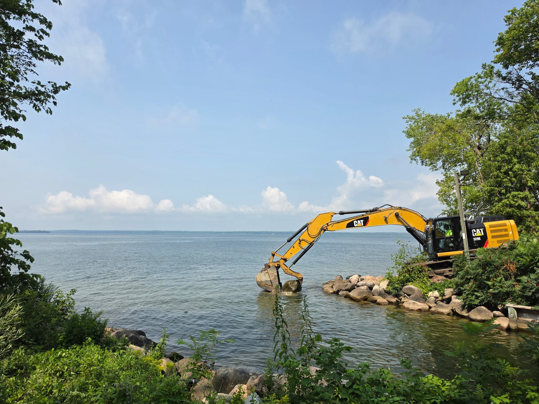 Storlie excavator placing rip rap along a lakeshore
