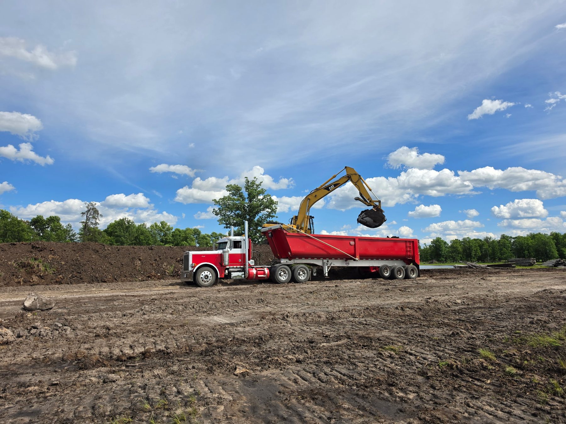 Red Storlie dump truck beside an excavator on a job site