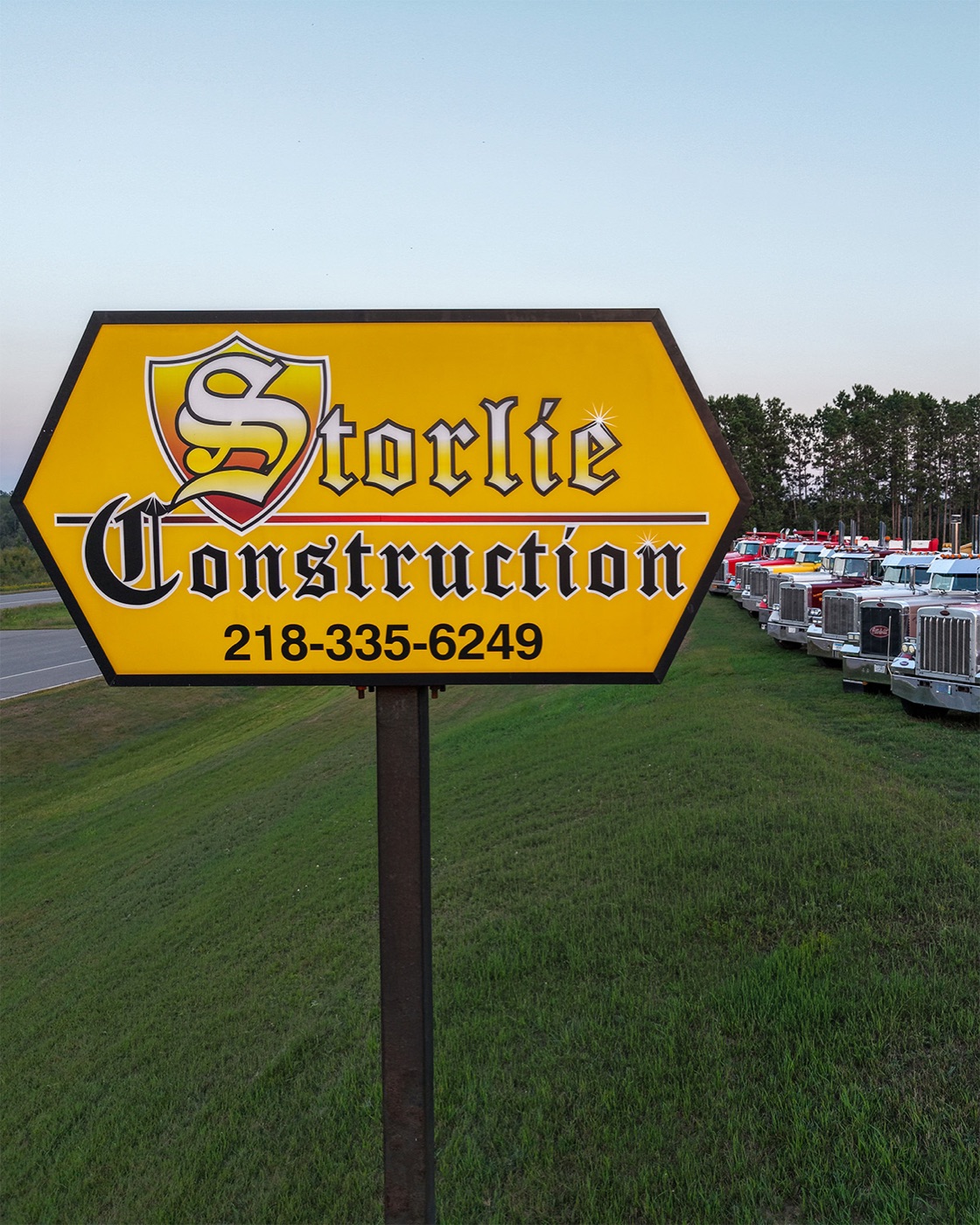 Storlie Construction sign with the company truck lineup behind it